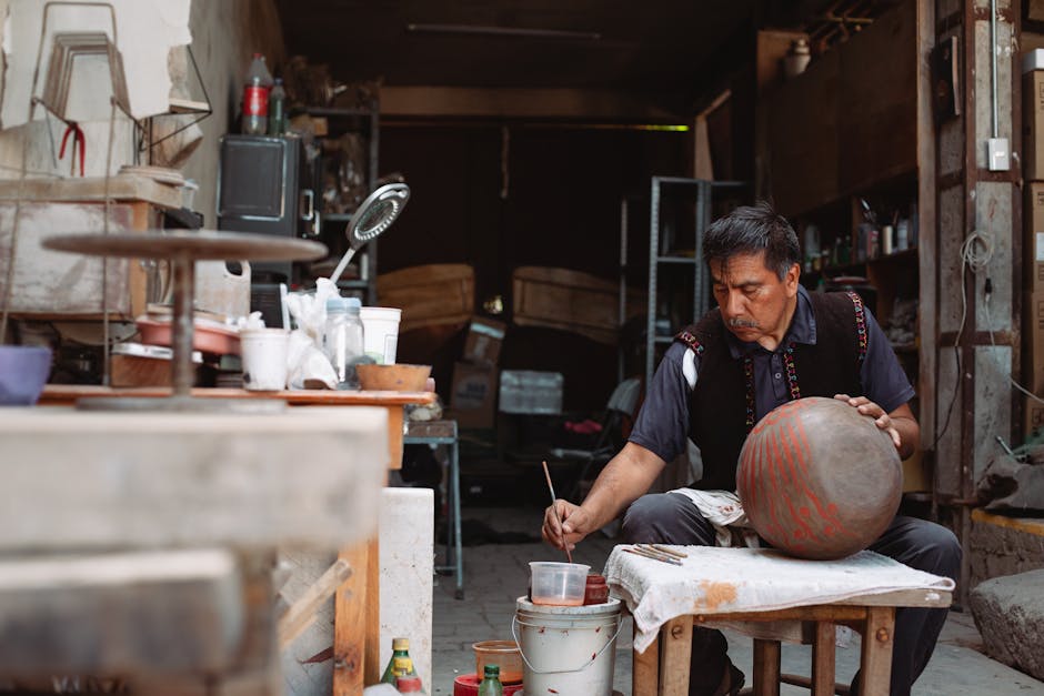 A skilled artisan painting pottery in a workshop, showcasing traditional craftsmanship.