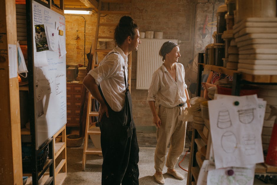 Two artisans collaborate in a rustic ceramic workshop filled with pottery creations.