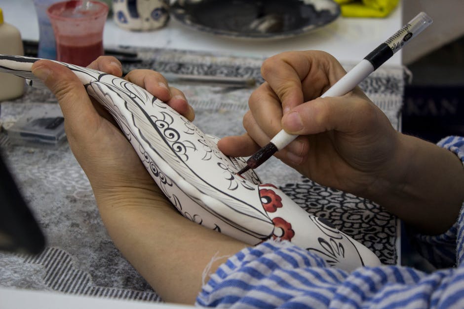 Close-up of an artisan delicately painting intricate patterns on a ceramic plate, showcasing traditional craftsmanship.